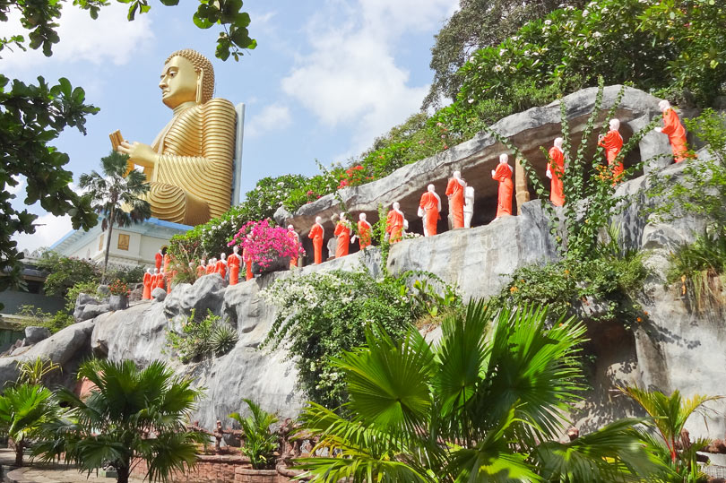 Monk statues at the side of the big buddha. Golden Temple, Sri Lanka.