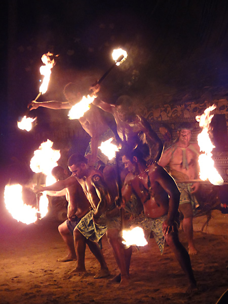 Fijian dancers form a human pyramid while spinning fire