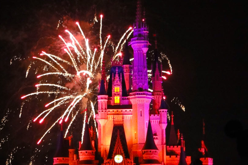Disney castle lit up pink during the fireworks display at Magic Kingdom, Orlando, Florida